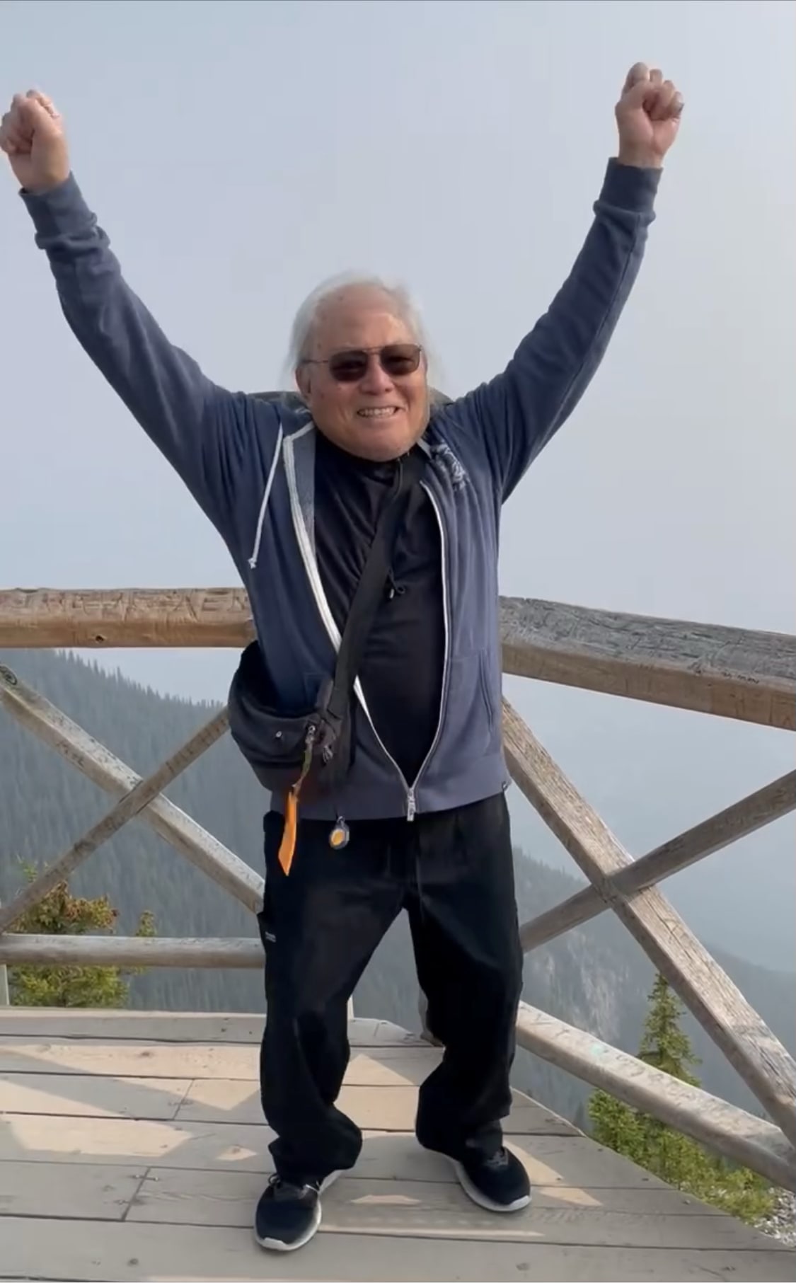 Dad celebrating with his arms raised at a mountain overlook