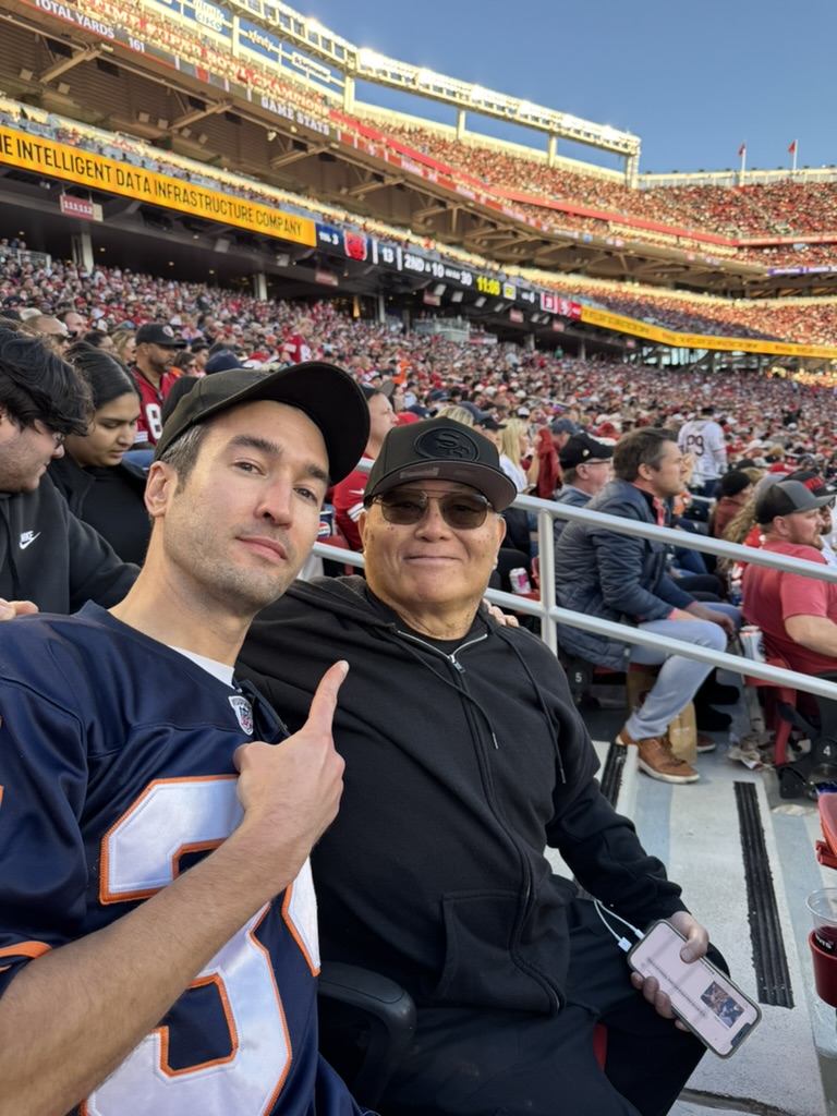 Dan and Gene cheering from the stands at a football game